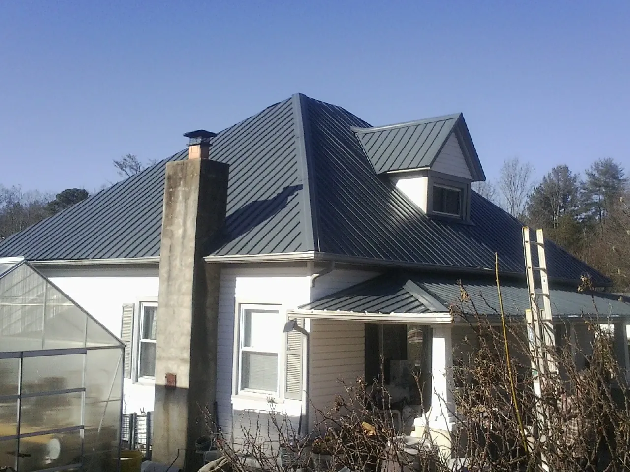 Dark blue standing seam metal roof on a white farmhouse with dormer — Slate & Tile Roof Repair by Roofing Brothers in Burnt Ranch