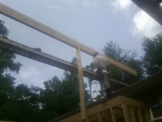Carpenter setting a ridge beam over a new addition frame — Ice Dam Removal by Roofing Brothers in Burnt Ranch