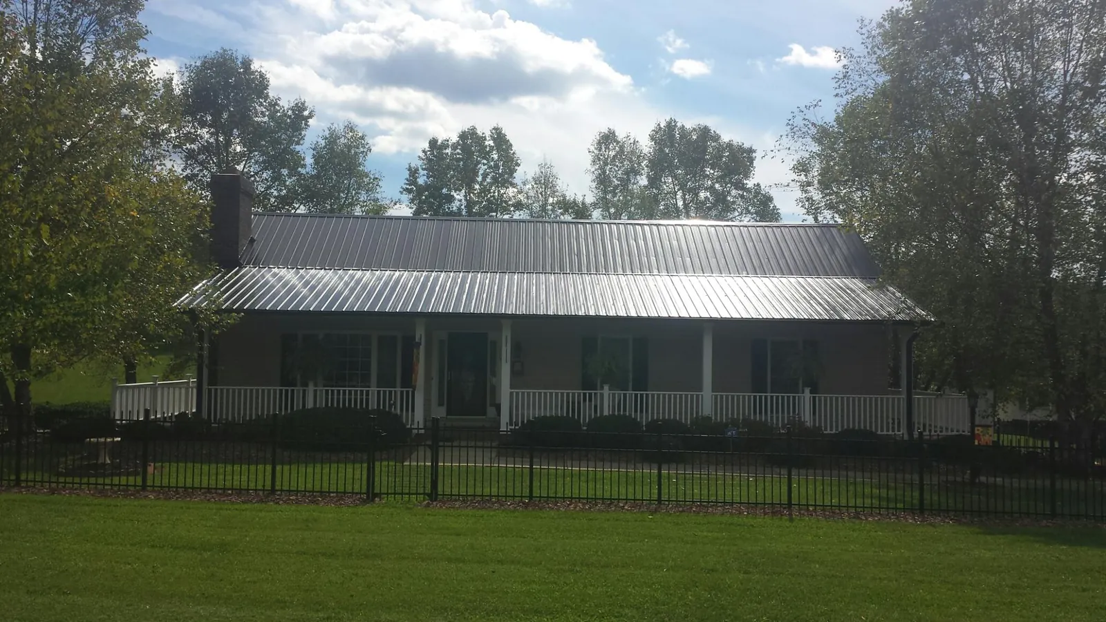 Gray metal roof on a brick ranch with a full width front porch — Gutter Guard Installation work by our crew in Burnt Ranch