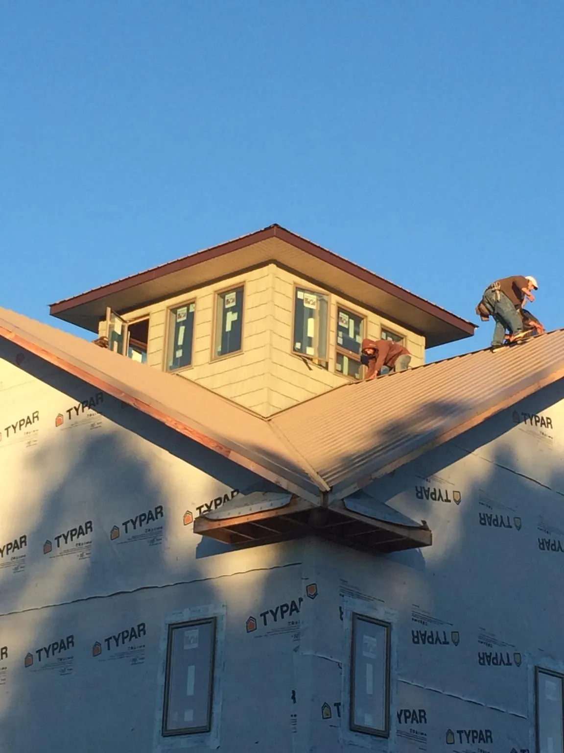 Roofers working around a rooftop cupola on a new metal roof at sunset — Roof Waterproofing in Burnt Ranch by Roofing Brothers